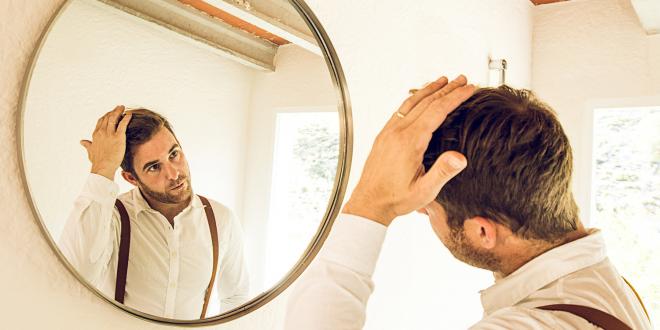 Man grooming his hair in front of a mirror.