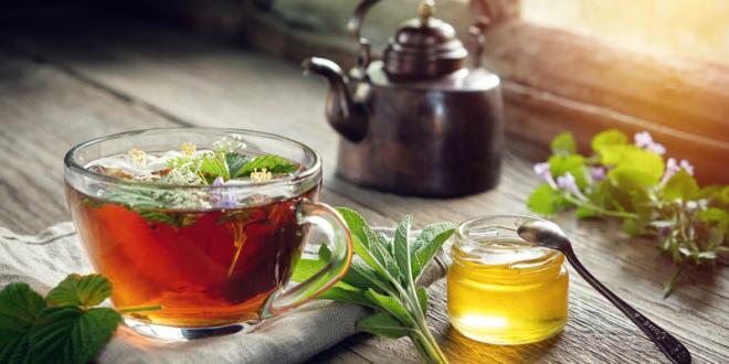 A cup of tea with fresh herbs and honey