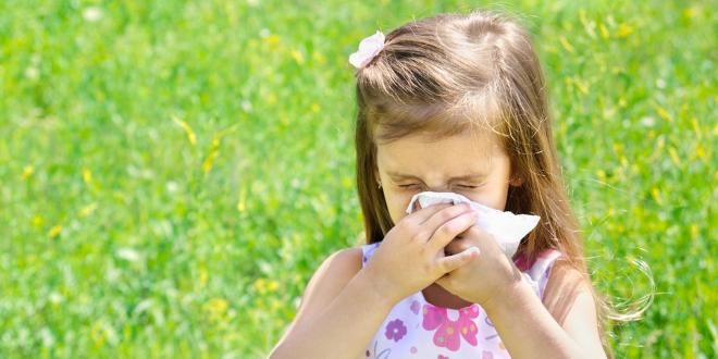 a girl sneezing in a summery field